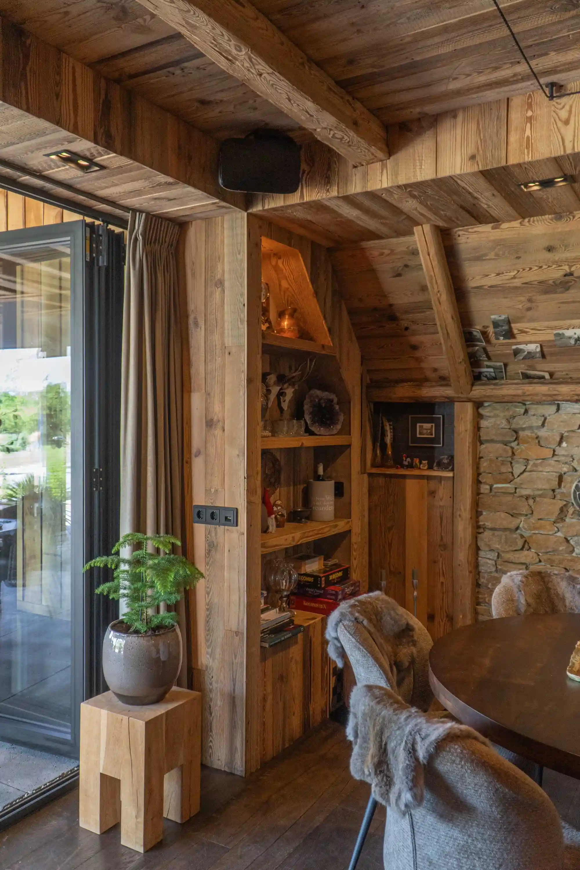 Oud grenen wandbekleding en maatwerk kasten zorgen voor een warme en authentieke uitstraling in deze sfeervolle tuinkamer.