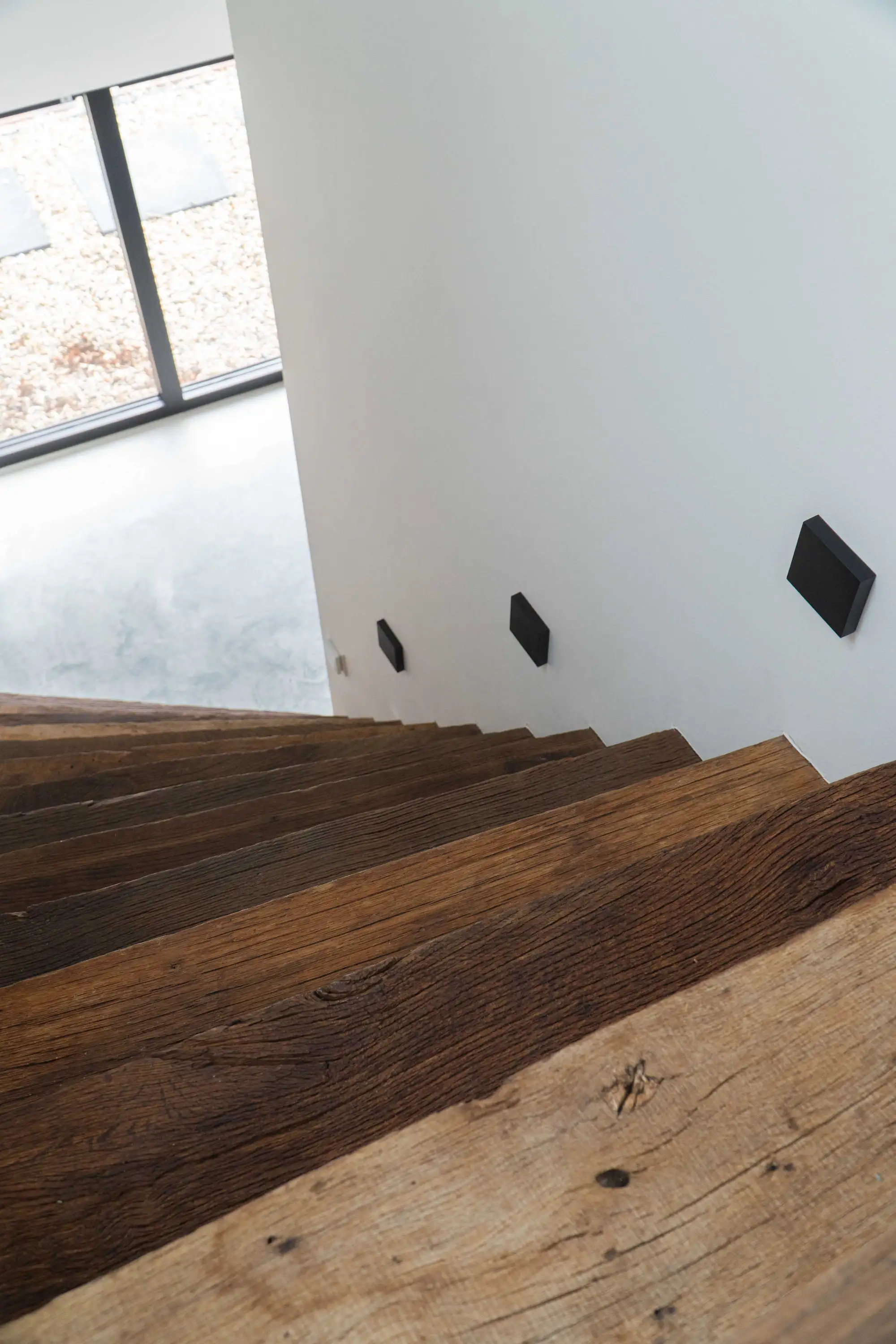 Detailopname van een oud eiken trap met zichtbare noesten, natuurlijke scheuren en een doorleefde structuur die het authentieke karakter van het hout benadrukt.