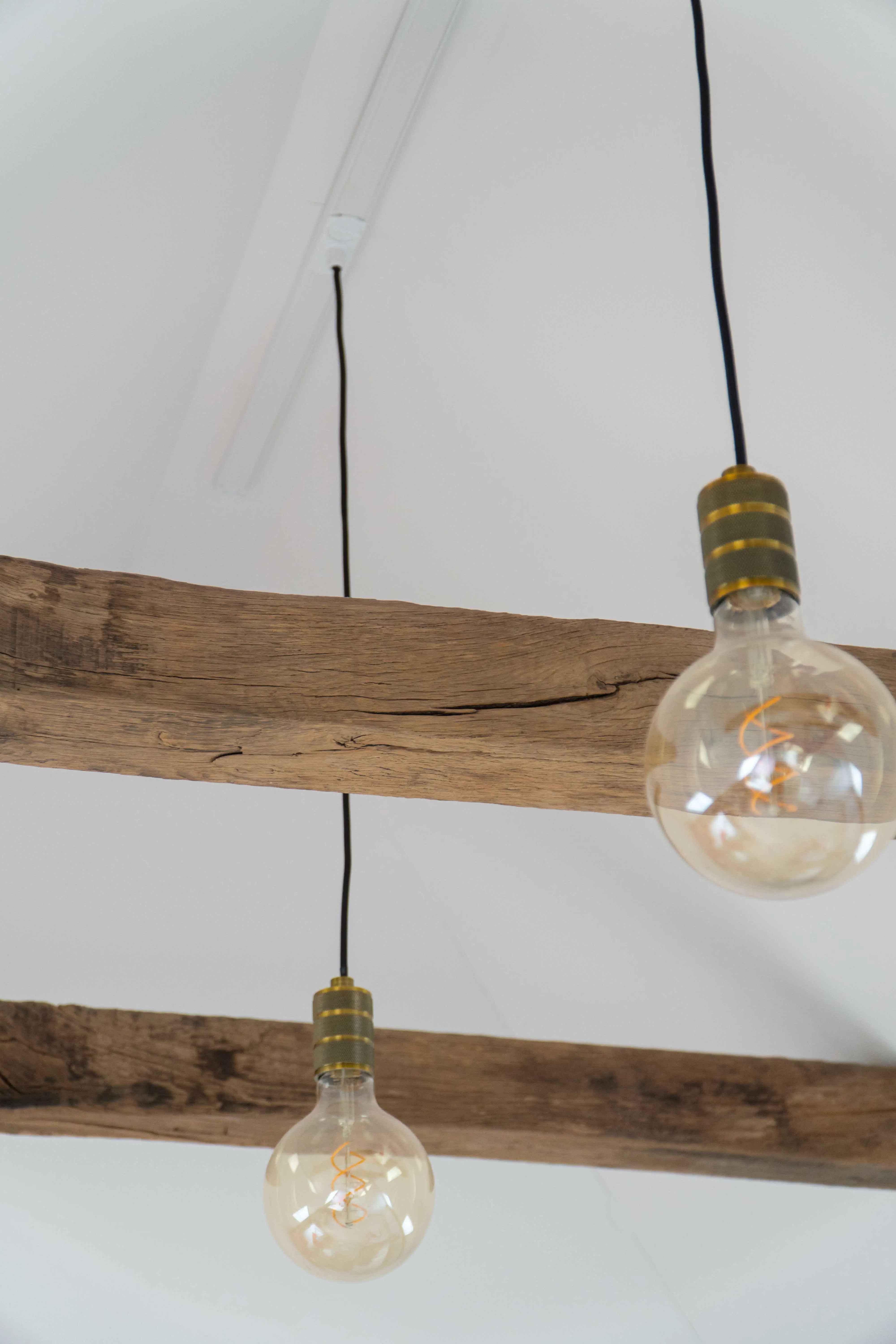 Historisch Hout eiken balken aan het plafond met hangende vintage gloeilampen, die zorgen voor een warme en authentieke uitstraling.